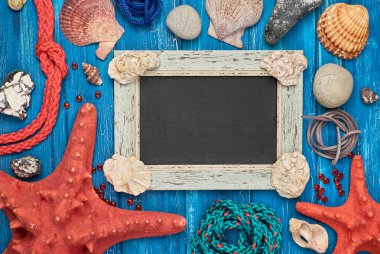 Deniz kabukları, taşlar, ip ve mavi ahşap arka plan üzerinde yıldız balık ile boş kara tahta, metin alanı