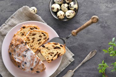 Paskalya Ekmeği (Almanca Osterbrot). Köy tahtasında taze yapraklar ve bıldırcın yumurtalarıyla geleneksel meyveli ekmeğin en üst görüntüsü. Paskalya kutlaması için geleneksel Alman tatlısı..