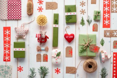 Çeşitli Noel ya da yeni yıl tatilleri çevre dostu dekorasyonlar, kağıt paketler ve yeniden kullanılabilir ya da sıfır atık hediye. Tahtaya yaslanmış, kurdele, kordon ve yemyeşil kutularla süslenmiş..