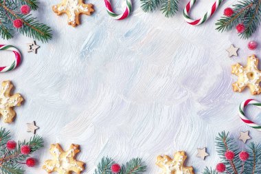 Noel çerçevesinde köknar dalları, şeker kamışları, donmuş böğürtlen ve kurabiyeler. Hafif desenli arkaplan, kopyalama alanı ile düz uzanır.