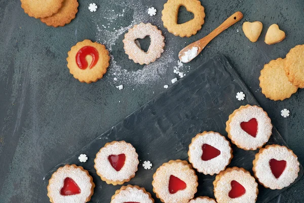 stock image Top view of traditional Christmas Linzer cookies with red jam on dark background. These are traditional Austrian filled bisquits.