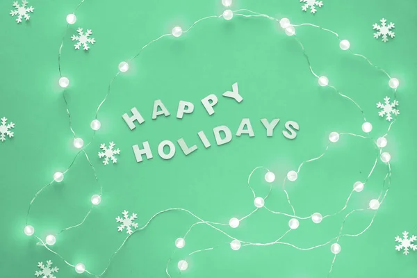 新年或圣诞模式公寓以 节日快乐 一文高瞻远瞩 新薄荷绿色背景上的纸雪花和节日彩灯的花环 时尚的单色色调背景 — 图库照片
