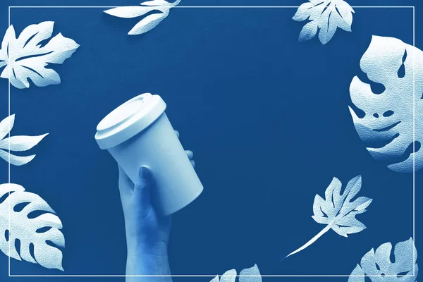 时尚可重复使用的生态咖啡杯 竹杯盖在手 单色蓝纸背景与白纸异国情调叶 纸工艺零浪费环保生活潮流 — 图库照片
