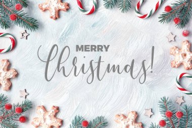 Beyaz, kırmızı ve yeşil tonlanmış Xmas çerçevesi. Dal dalları, baston şekerler, böğürtlenler ve kurabiyeler. Hafif desenli arka plan, düz yatış 