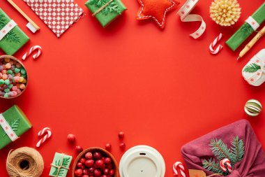 Kırmızı, yeşil ve beyaz Xmas geçmişi. Moda dostu sıfır noel ziyanı ve yeni yıl süslemeleri ve hediyeleri. Geometrik daire, hediyeler, dekorasyonlar, süslü kutular ve baston şekerlerle yatıyordu..