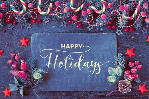 圣诞背景与杉树枝条 红色浆果和糖果手杖与黑色板纹理深蓝色背景 贴上印有 节日快乐 字样的黑色圣诞贺卡 — 图库照片