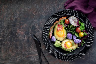Yumurta ve pastırmalı avokado, fotokopi uzayı ile koyu arka planda yatar.