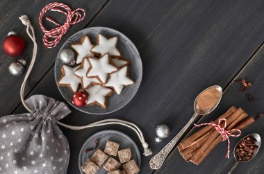Noel arkaplanı gri, beyaz ve kırmızı, koyu ahşap. Noel kurabiyeleri, baharatlar ve dekorasyonların en üst görüntüsü. Tonu ayarlanmış resim, metin alanı