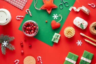 Kırmızı ve yeşil Xmas geçmişi. Moda dostu sıfır noel ziyanı ve yeni yıl süslemeleri ve hediyeleri. Geometrik dairede hediyeler, dekore edilmiş kutular, bambu kahve kupası ve çizgili şeker kamışları vardı..