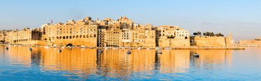 Sabah Valetta Limanı, sabah ışığında Senglea Yarımadası Grand Valetta Körfezi 'nin sakin sularına yansıyor. Panoramik resim, pankart bileşimi.