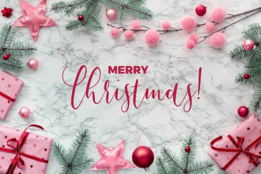 Panoramik Noel dairesi beyaz mermerin üzerinde, hediye paketlerinden yapılmış kenarları, doğal yeşil köknar dalları, kırmızı ve pembe ıvır zıvırlar. 