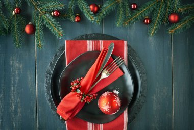 Koyu arka planda Noel menü konsepti. Yeşil ve kırmızı Noel süslemeleri ile siyah tabak ve vintage çatal. 