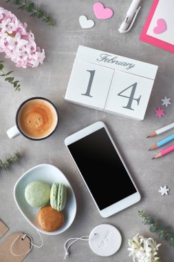 Mutlu Sevgililer! Sabah kahvesi, ahşap takvim, badem kurabiyeleri, kalemler, pembe sümbül çiçekleri ve gri taş masadaki okaliptüs, düz bir görünüm..