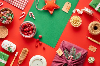 Kırmızı ve yeşil Xmas geçmişi. Moda dostu sıfır noel ziyanı ve yeni yıl süslemeleri ve hediyeleri. Geometrik dairede hediyeler, dekore edilmiş kutular, bambu kahve kupası ve çizgili şeker kamışları vardı..