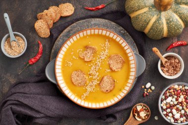 Balkabağı, karışık fasulye ve seramik kasede tatlı patates kreması çorbası, malzemeler ve baharatlarla üst manzara.