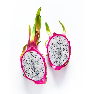 Beyaz zemin üzerinde taze organik pembe, beyaz ve yeşil ejderha meyvesi (pitaya veya pitahaya) bulunan yaratıcı düzlem. Modaya uygun üst manzara, meyvenin ikiye bölünmüş hali..