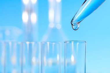 Bilimsel arkaplan: cam test tüpünün üstündeki pipetten bir damla üzerine yakın plan, metin alanı 
