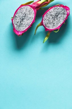 Taze organik ejderha meyvesi (pitaya veya pitahaya) mavi nane arkaplanından ikiye bölünmüştür. Fotokopi alanı olan yaratıcı düz bir düzen. Canlı, koyu pembe ve yeşil renkli egzotik meyveler. Tek ejderha meyvesi modayla ikiye bölünmüş yaratıcı düz bir düzen.