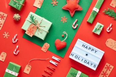 Kırmızı ve yeşil Xmas geçmişi. Çevre dostu sıfır israf Noel ve yeni yıl süslemeleri. Geometrik dairede hediyeler, kutular, askılar, kahve fincanları ve oyuncaklar vardı. 