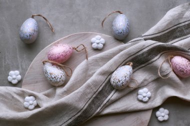 Dekoratif el yapımı Paskalya yumurtaları ahşap tepside keten havluyla pastel renklerde.