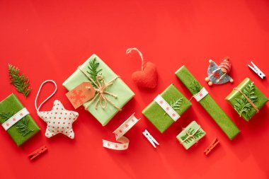 Kırmızı ve yeşil Xmas geçmişi. Eko-Sıfır Noel 'i ya da yeni yıl hediyelerini boşa harcıyor. Geometrik köşegen yatıyordu. Geri dönüşümlü kağıda sarılmış kutular kablo veya pamuk kurdeleyle bağlanmış ve yeşil yapraklarla süslenmiş..