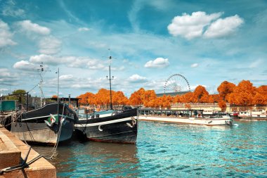 Sonbaharda güzel Paris. Kıyıya demirlemiş tarihi tekneleri ve geçen yolcu gemisiyle Seine nehir kıyısı. Bu resim tonlandırılmış. 