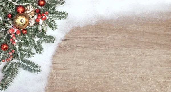 Karda süslenmiş Noel ağacı dallarıyla Noel arkaplanı. Tahtada kopyalama alanı olan üst görünüm.