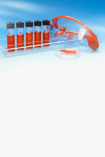 Vertical scientific background in blue and red, space for your text. Biological or medical samples and safety glasses on blue gradient background