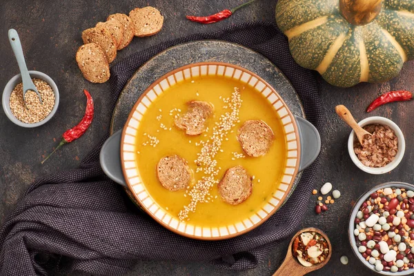 Balkabağı, karışık fasulye ve seramik kasede tatlı patates kreması çorbası, malzemeler ve baharatlarla üst manzara.