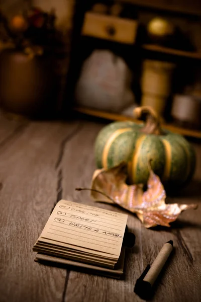 Open notebook with handwritten resolutions on wooden table on the wintage kitchen with Autumn decorations. Shallow DOF, focus on the page. This image is toned