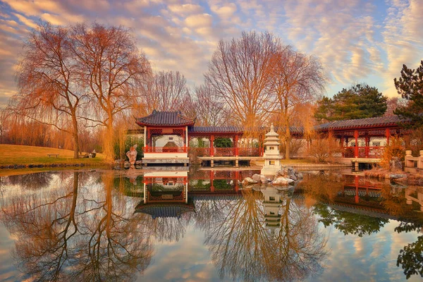 Resmi Çin bahçesinin sonbahar manzarası dekoratif pavyonu ve günbatımında ahşap bir pagoda ile gölde yansıması olan.