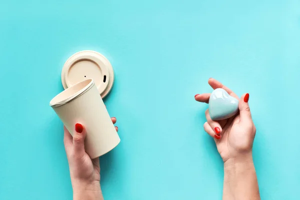 スタイリッシュな再利用可能なエココーヒー旅行マグカップ 女性の手で蓋とセラミックの心を持つ竹のカップ ブルーミントアクア紙の背景をメンズ 廃棄物ゼロ 環境に優しいライフスタイルトレンド — ストック写真