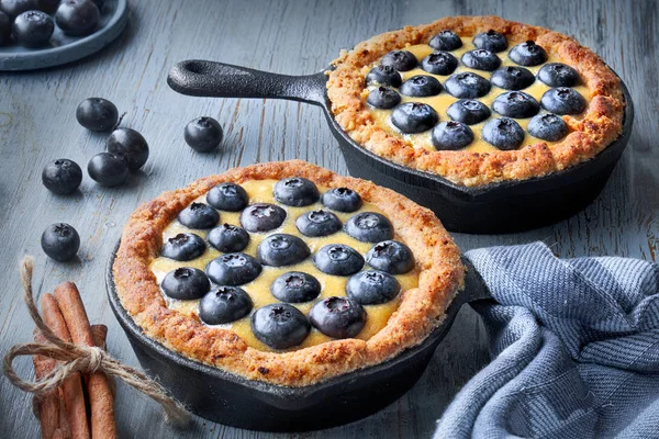 Gri ahşap arka planda vanilyalı kremalı lezzetli yabanmersinli tartlar.