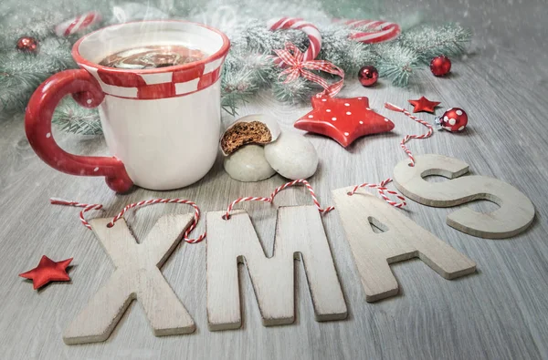 Wooden letters "Xmas", cup of steaming tea and winter decoration — Stock Photo, Image