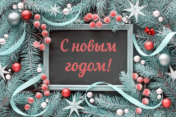 Happy New Year text in Russian language. Christmas frame in green and red, top view, flat lay. Fir twig decorated with baubles, berries and stars — Stock Photo, Image