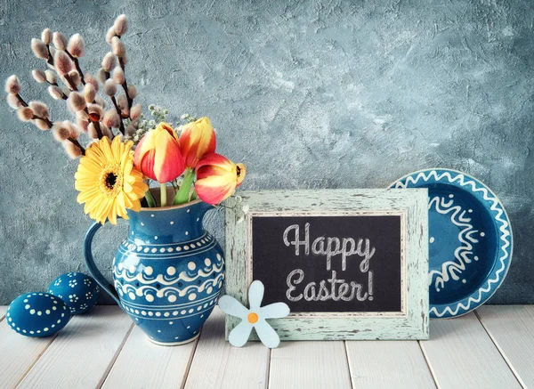 Flores de primavera en jarra de cerámica azul con placa a juego y E —  Fotos de Stock