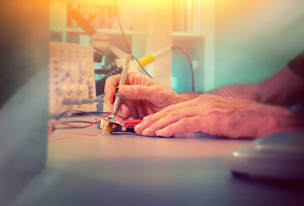 Hands of a senior male engineer testing electronic equipment