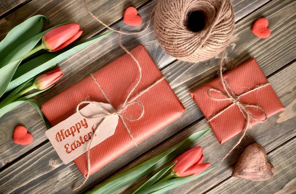 Układ wielkanocny: czerwone tulipany, zapakowane prezenty, sznurek i decorati — Zdjęcie stockowe