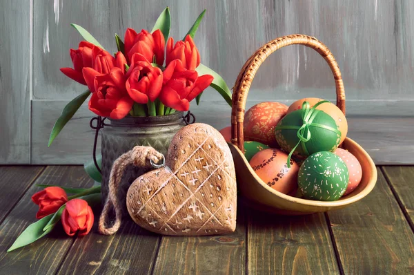 Påsk sammansättning med röda tulpaner, trä hjärta och en korg med — Stockfoto