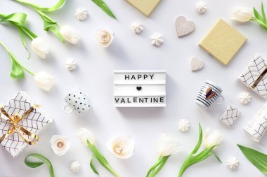 Sevgililer Günü düz yatıyordu, beyaz arkaplanda beyaz lale çiçekleri, kahve fincanları, geometrik kağıda sarılı altın çizgiler ve şekerlemeler. Işık panosunda 