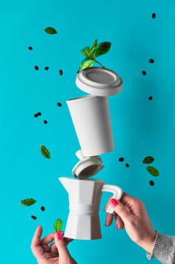 Hiçbir atık kahve piramidini mavi naneli arka planda kadınların ellerinde dengelemek. Seramik espresso kahve makinesi ve çevre dostu yeniden kullanılabilir bambu kahve kupası. Kahve çekirdekleri ve yapraklar..