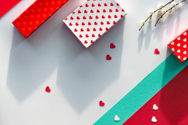 Sevgililer Günü düzlüğü, üst manzara kırmızı, beyaz ve yeşil nane renkleri. Geometrik iki tonlu bölünmüş kağıt arka plan hediye kutuları, hissedilmiş kalp ve vajina söğüt çiçekleri. Sevgililer günün kutlu olsun.!