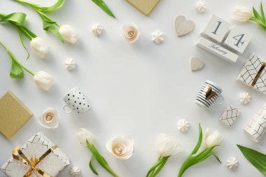 Sevgililer Günü düzlüğü, beyaz arka planda beyaz lale çiçekleri, kahve fincanları, altın çizgili sevgililer günü hediyesi, şekerlemeler. 14 Şubat tarihli ahşap takvim, kopyalama alanı.