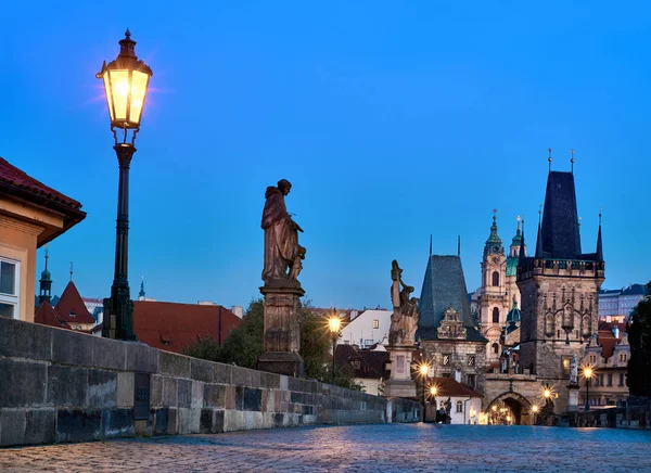 Karlův most za úsvitu, silueta Mostní věže a světské sochy s osvětlenou pouliční lampou v Praze — Stock fotografie