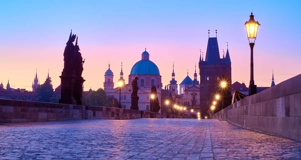 Karlův most v dopoledních hodinách, silueta Mostní věže a sochy světců s pouličními světly v Praze — Stock fotografie