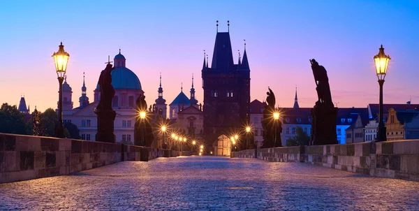 Карлов мост на рассвете, силуэт башни моста и скульптуры святого с уличным освещением в Праге, Чехия — стоковое фото