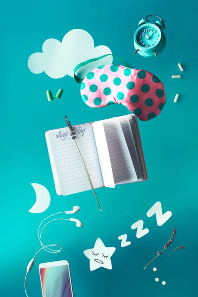 Friska natt sömn kreativt koncept med sömnlogg handskriven dagbok. Flygande eller leviterande föremål: sovmask, väckarklocka, hörlurar, öronproppar och piller. Papper måne stjärna och moln, sömnig stjärna. — Stockfoto