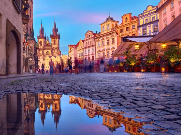 St Mary Tyn kyrkan i Prag med reflektion i en pool av vatten efter sommarregn med turister som går förbi mot torget i Gamla Stan. Romantiska Prag, resa bakgrund vid solnedgången. — Stockfoto