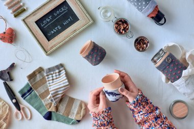 Zero waste household. Making bamboo cup and thermos can sleeve out of stray socks. Upscale of orphaned mismatched socks. Flat lay on textile tablecloth. Low impact eco friendly lifestyle.