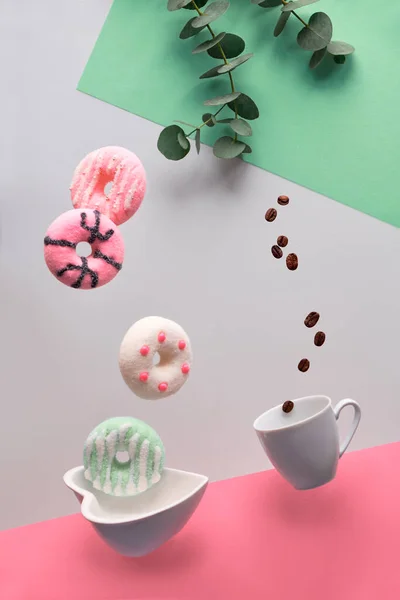 St. Valentine concept, levitation of pink and green doughnuts above heart shaped bowl. Coffee beans fly in espresso coffee cup. Creative background in pink, green mint and light grey colors. — ストック写真